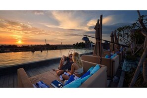 Relax in a tranquil rooftop setting with lounge chairs and a shaded pergola, taking in the serene view of the water.