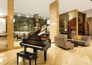 Relax in style with a grand piano, comfortable seating, and stunning views of lush greenery.