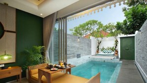 Ein modernes Zimmer mit Pool, einer Couch, einem Tisch mit Frühstücksangeboten und Blick ins Freie.