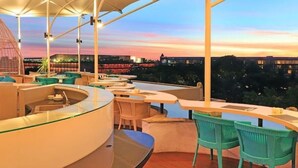 An outdoor bar area with seating and a view of the city skyline at dusk. - Whirlpool Suite Room In Seminyak (Bali)