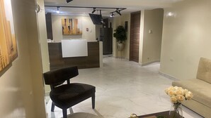 A modern living room with a dark patterned chair, a beige sofa, and a coffee table with decorative items. - Hotel Sada (Guayaquil)
