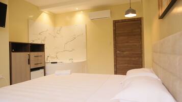 A bedroom with a bed, a wooden wardrobe, a bathroom with a marble wall, and a hanging light fixture.