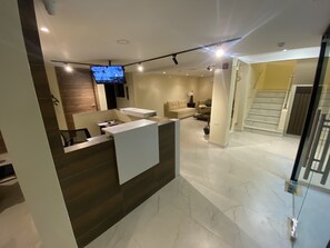 A modern living area with a sofa, a coffee table, and a TV mounted on the wall. - Hotel Sada (Guayaquil)
