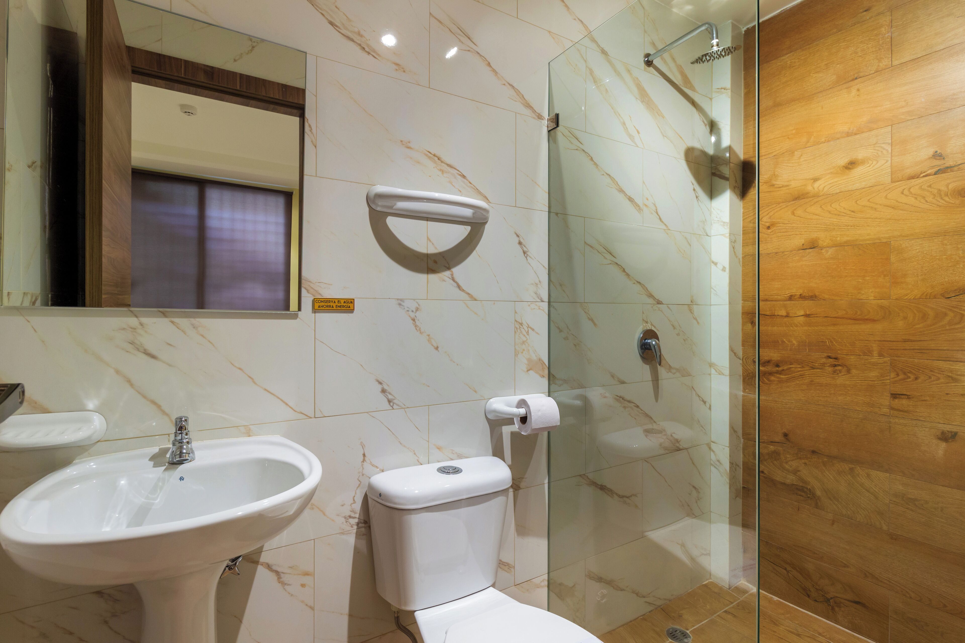 A bathroom with a sink, toilet, and glass shower enclosure.