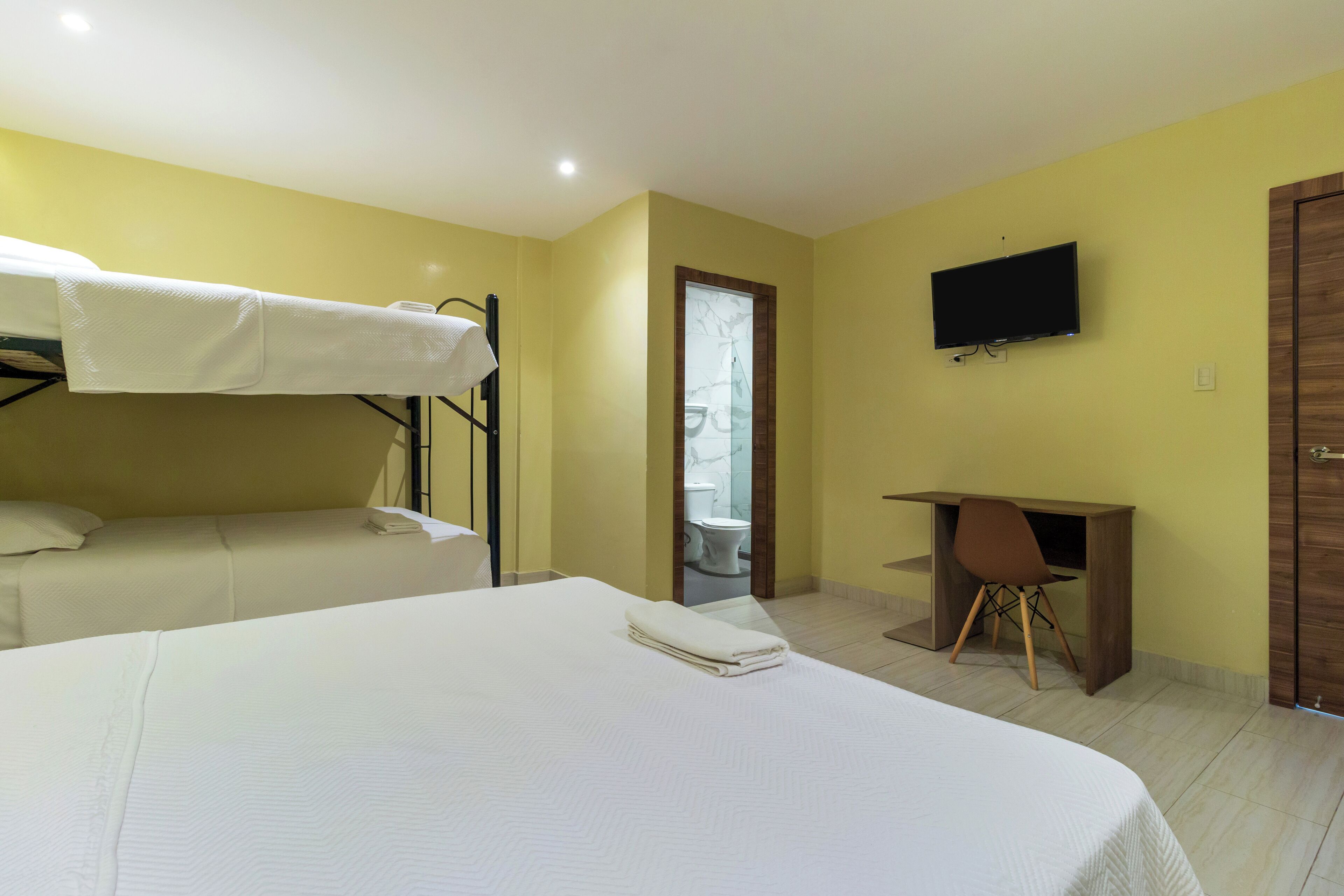 Una habitación de hotel con literas, un escritorio y un televisor.