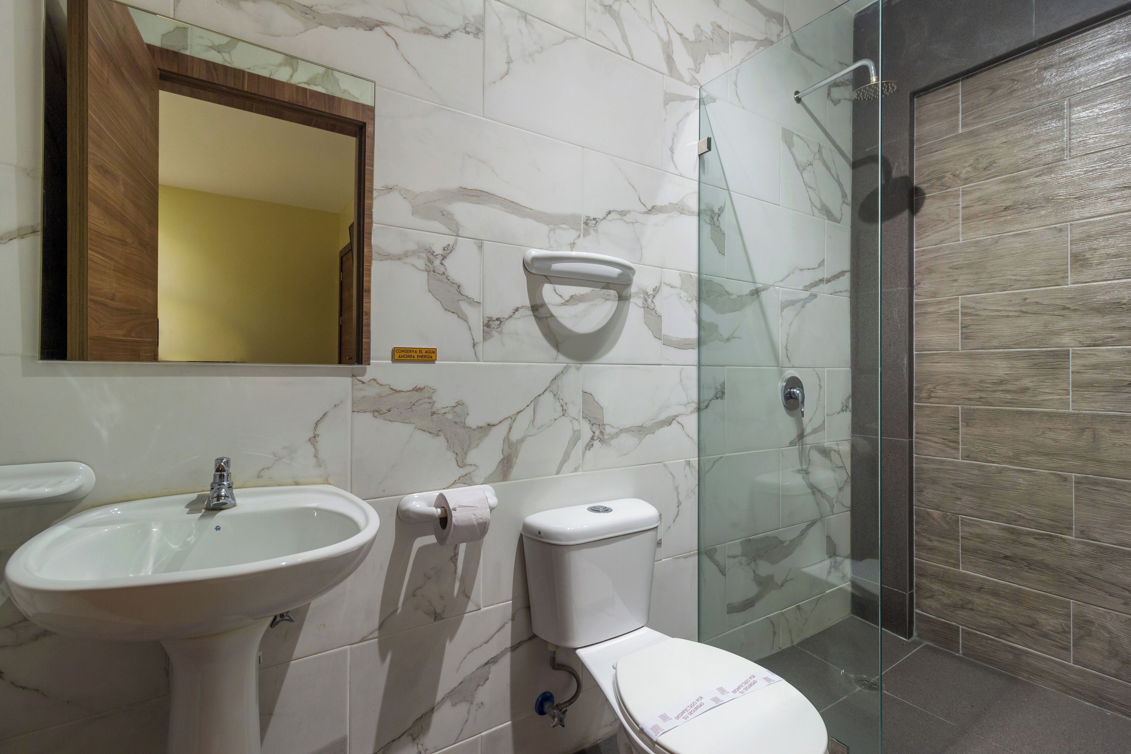 A bathroom with a marble sink, toilet, and glass shower enclosure.
