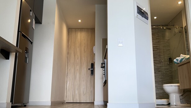 Une cuisine moderne dotée d’un réfrigérateur encastré, d’une porte en bois et d’une cabine de douche en verre.