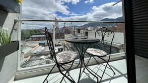 Un balcon doté d’une balustrade en verre, de deux chaises et d’une petite table.