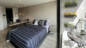Une chambre moderne avec un grand lit, un bureau et un balcon agrémenté de plantes.
