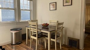 A dining area with a wooden table and chairs, a trash can, and a window with a view. - Elegant house near Lake Michigan & Lambeau Field (Two Rivers)
