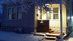 A house with a snow-covered front yard and a lit porch. - Elegant house near Lake Michigan & Lambeau Field (Two Rivers)