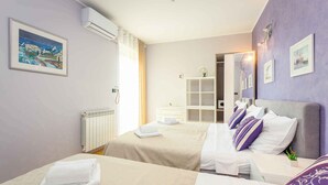 Ein Hotelzimmer mit zwei Betten, einem weißen Schminktisch, einem Spiegel und einem Fenster mit Vorhängen.