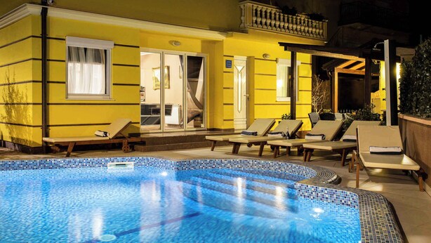 Ein Swimmingpool mit Liegestühlen und ein gelbes Gebäude mit Balkon.