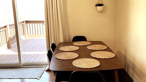 A dining table with six woven placemats, a hanging light fixture, and a view of a wooden deck through a sliding glass door. - NEW! ARK Family Retreat w/ Game Room 3min to Ark! (Williamstown)