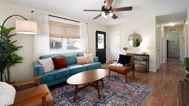 A living room with a blue sofa, a wooden coffee table, a floor lamp, and a ceiling fan. - NEW! ARK Family Retreat w/ Game Room 3min to Ark! (Williamstown)