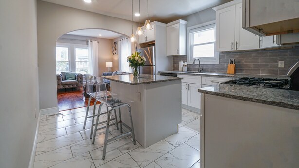 A modern kitchen with white cabinets, a central island, and a stainless steel refrigerator. - Faboulous and Cozy Apartment in Montclair, NJ (Montclair)