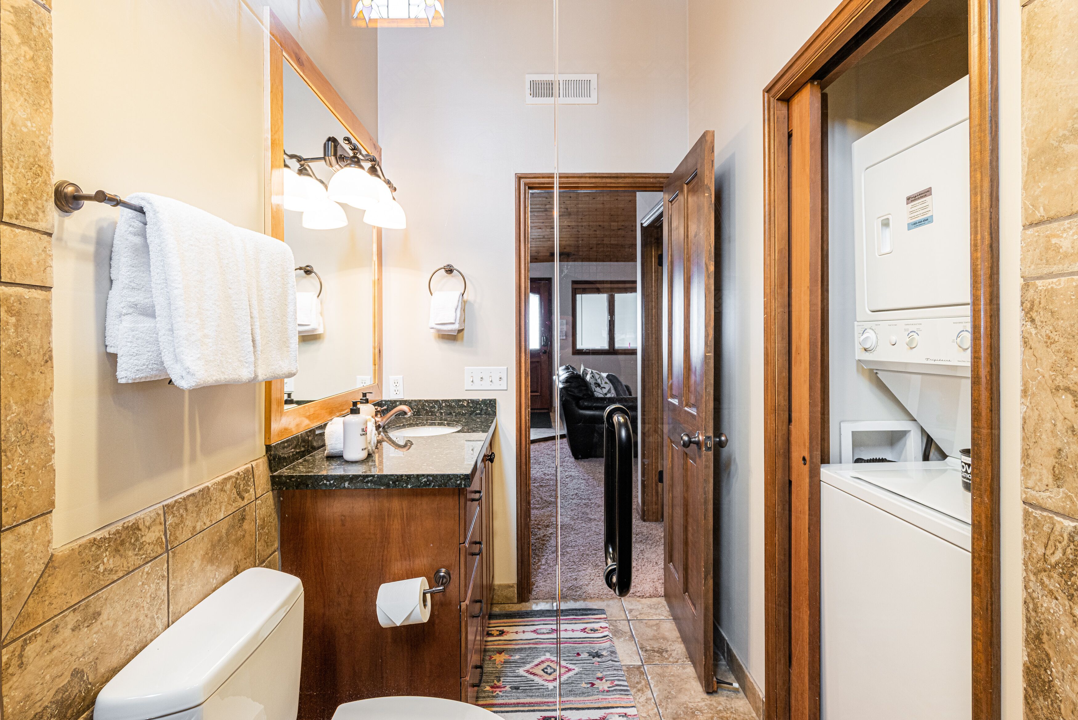 A narrow hallway leading to a bathroom with a toilet, sink, and a washing machine.