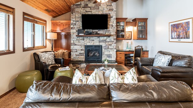 A cozy living room with a stone fireplace, leather sofas, and a ceiling fan. - Park City Motherlode F is in a Great Location with Year-Round Recreation! (Park City)