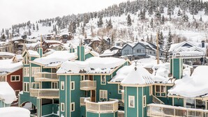 A multi-story building with balconies, surrounded by snow-covered trees and a mountainous backdrop. - Park City Motherlode F is in a Great Location with Year-Round Recreation! (Park City)