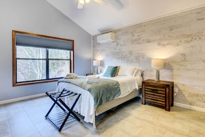 Relax in a serene bedroom with a large window, a comfortable bed, and a bedside table with a lamp.