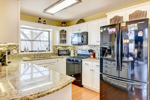Enjoy cooking in this well-lit kitchen with a refrigerator, microwave, and gas stove.