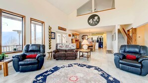 A spacious living room with two leather recliners, a large floral rug, and a view of the kitchen and dining area. - Hot Tub, Decks & More! Serene Maggie Valley Home (Maggie Valley)