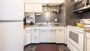 A modern kitchen with white cabinets, a stainless steel sink, a microwave, and a stove.
