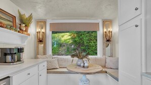 A cozy kitchen nook with a built-in bench, a round wooden table, and a decorative vase. - Tuscan River Retreat with Scenic River Views  (York)