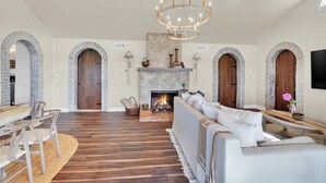 A spacious living room with a fireplace, wooden flooring, and a chandelier. - Tuscan River Retreat with Scenic River Views  (York)