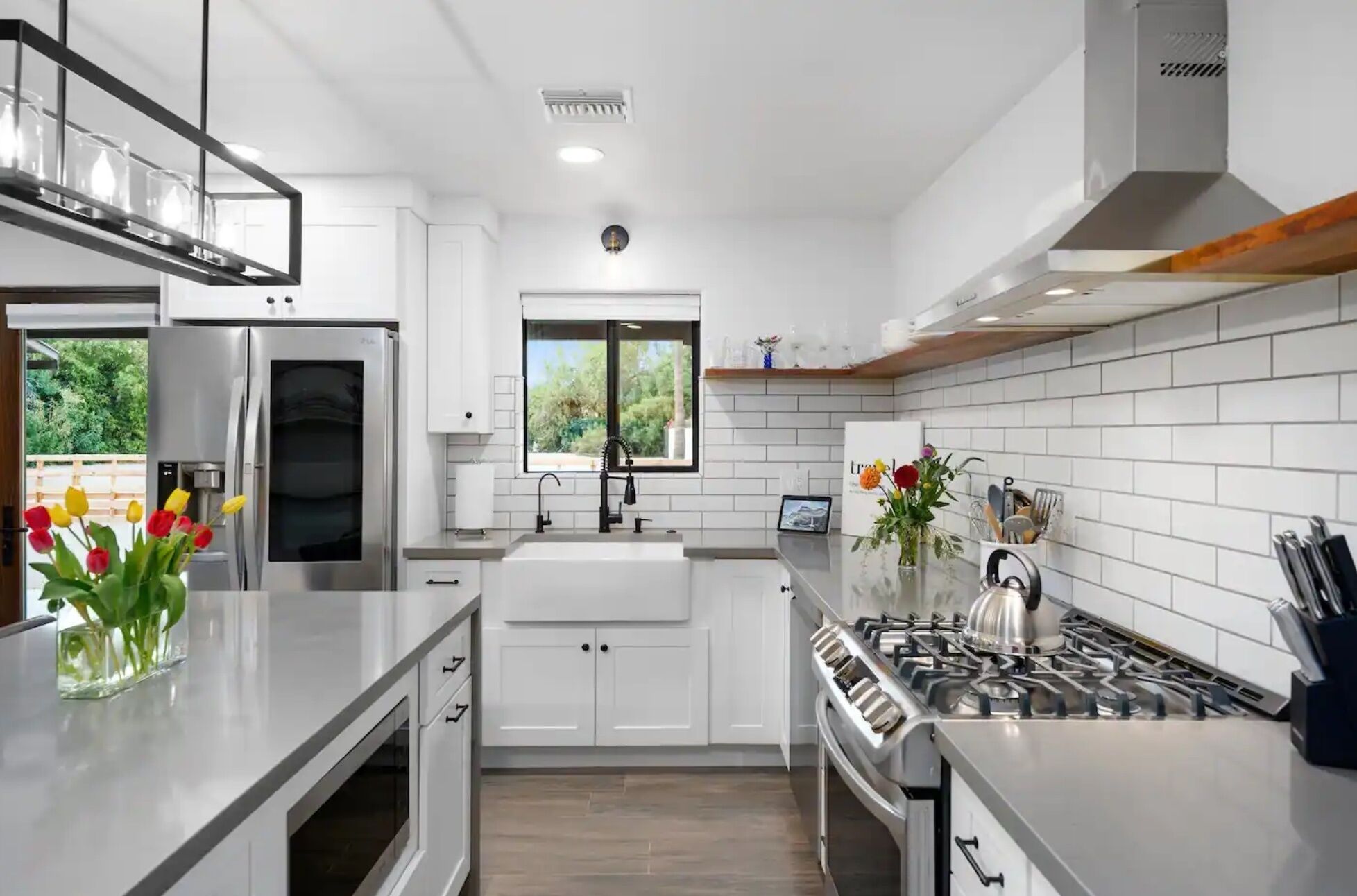 A modern kitchen with white cabinetry, a stainless steel stove, and a window providing natural light.