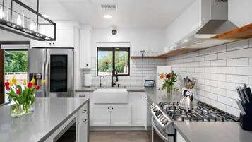 A modern kitchen with white cabinetry, a stainless steel stove, and a window providing natural light.