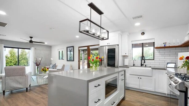 A modern kitchen with white cabinetry, a central island, and a built-in oven.