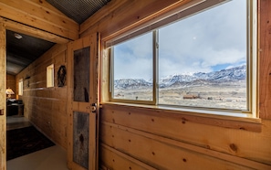 Un intérieur en bois avec une grande fenêtre donnant sur des montagnes enneigées.