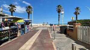 A street with shops on one side and a pedestrian path. - Studio 2 Personnes Proche Plage et Commerces - 2phoe504 (CANET PLAGE)