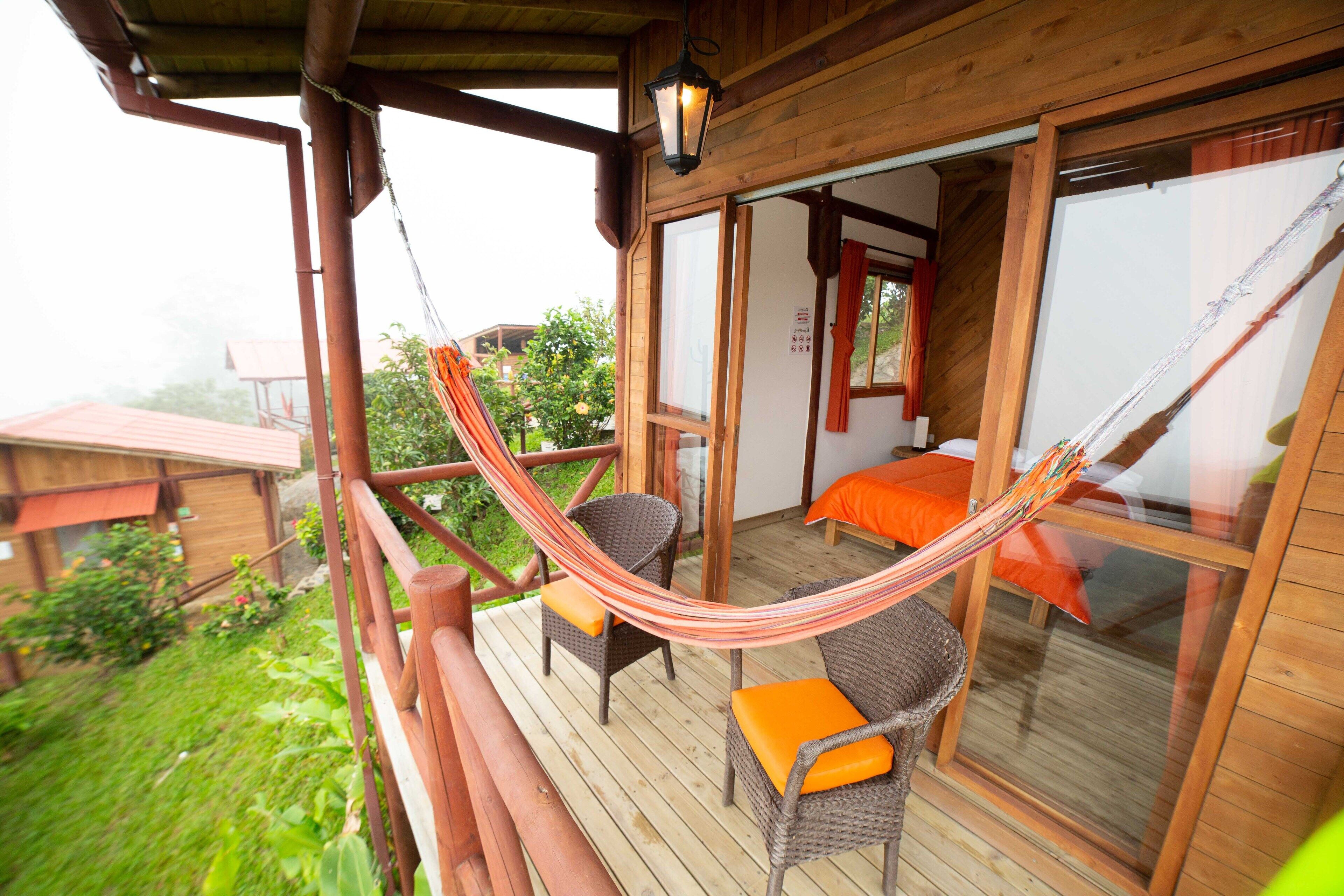 A wooden deck with wicker furniture and a hammock.