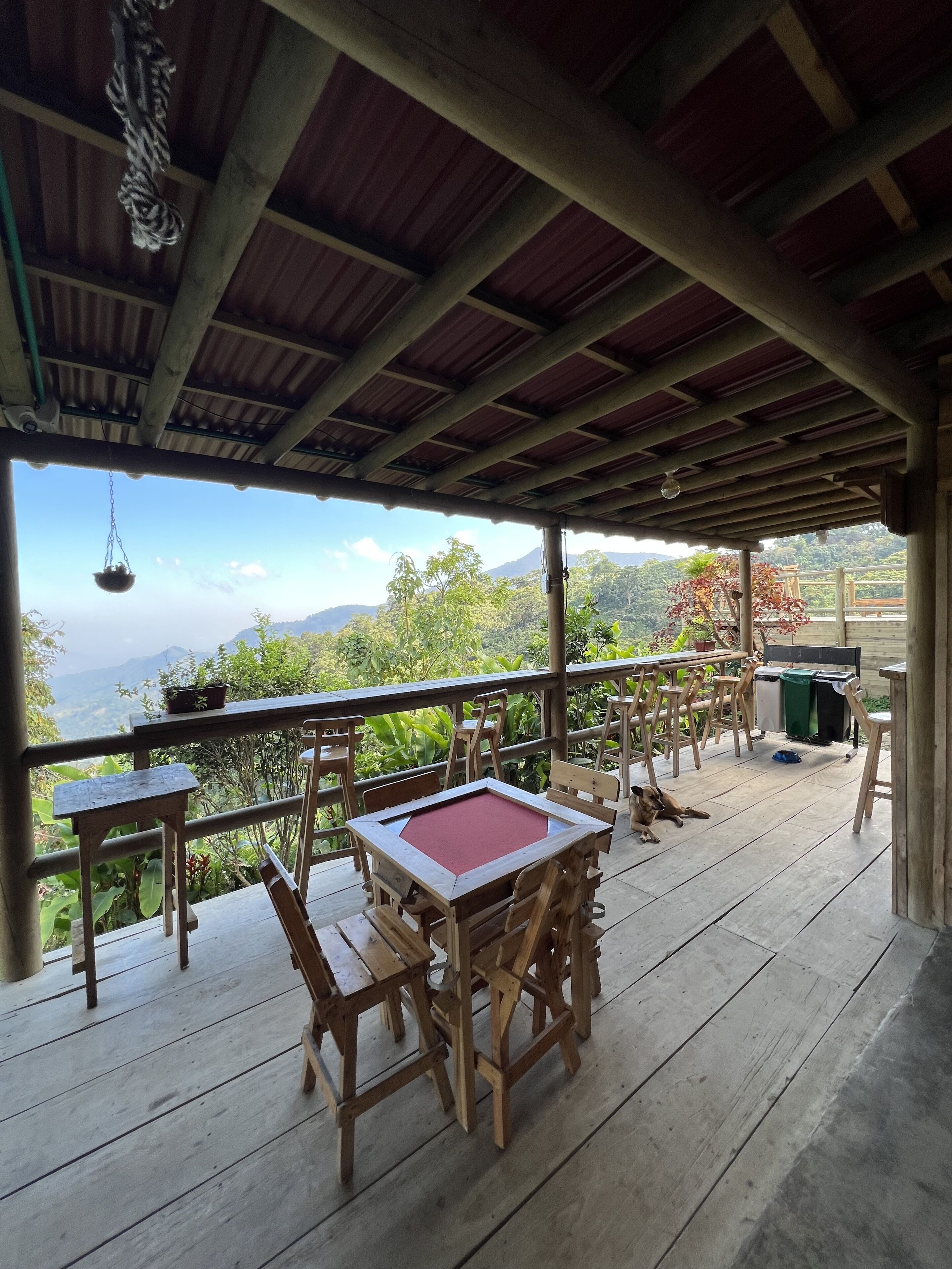 A wooden deck with a table and chairs, overlooking a mountainous landscape.