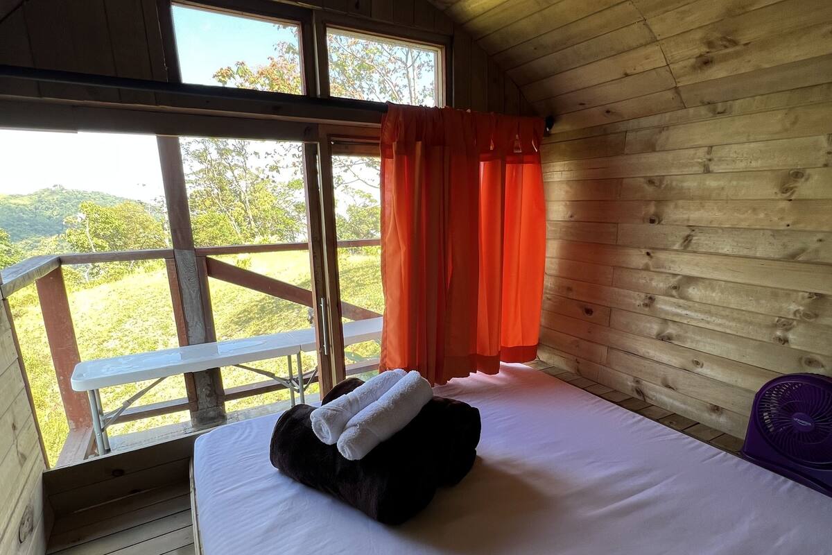 Une pièce de style cabane en bois, avec un lit, une fenêtre et une vue sur l’extérieur.