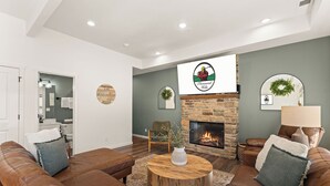Un salon moderne avec une cheminée en pierre, des canapés en cuir et une table basse ronde en bois.