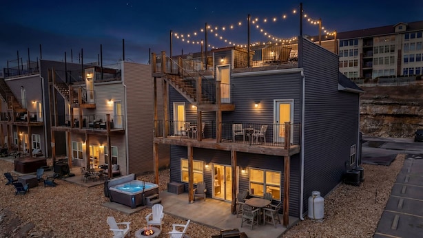 Un immeuble à plusieurs étages doté d’espaces extérieurs aménagés pour s’asseoir, d’un jacuzzi et de guirlandes lumineuses.