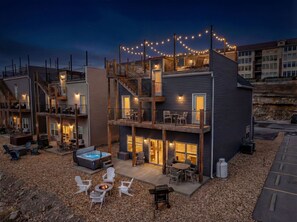 A multi-story building with outdoor seating areas, a hot tub, and string lights. - Lakeside Lodge • 6BR Lakeview Retreat • Rooftop Deck + Hot Tub • Sleeps 16 (Branson)