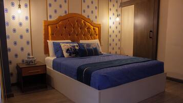 A neatly made bed with a wooden headboard, a bedside table, and patterned wallpaper.