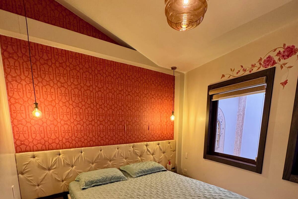 A bedroom with a bed, a window, and a patterned wall.