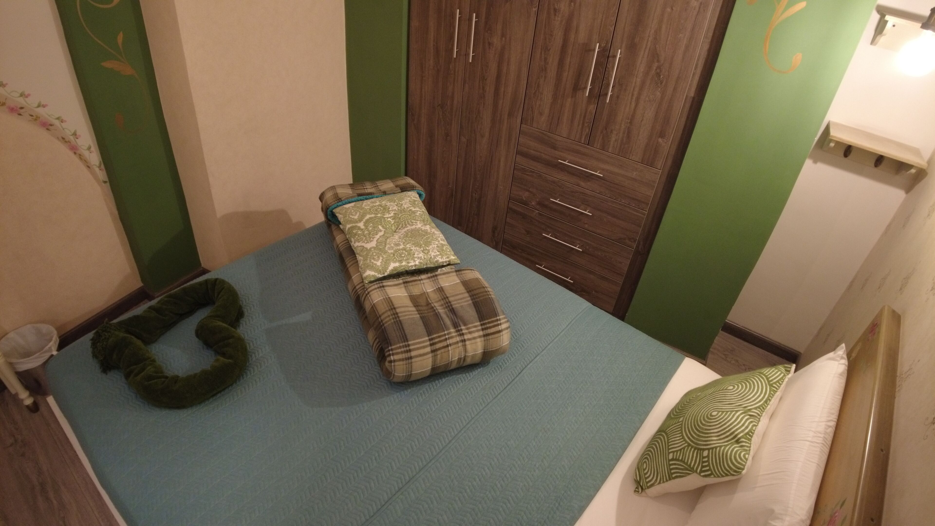 Un dormitorio con una cama, una pared verde y un armario de madera.