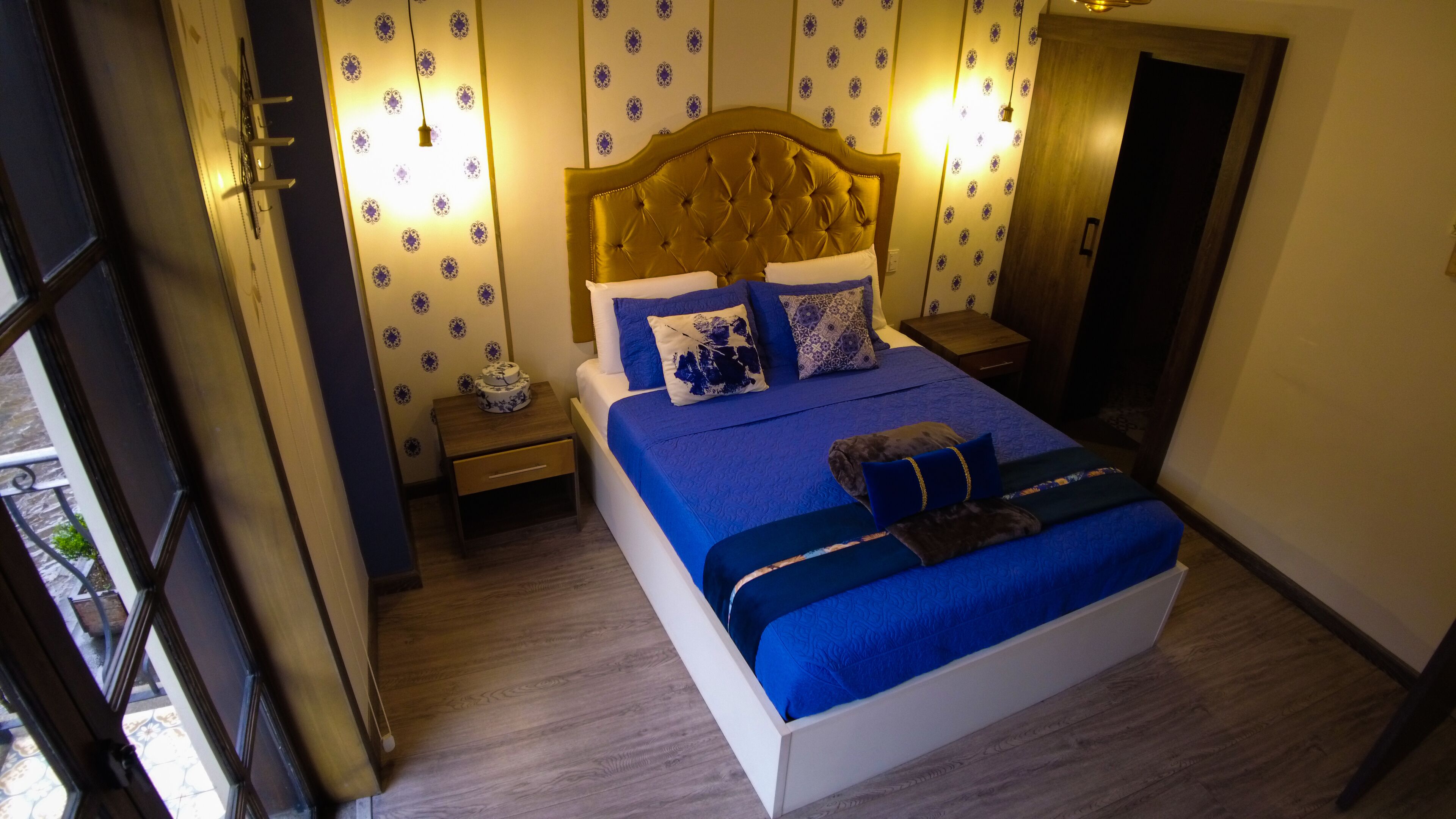 Un dormitorio con una cama grande, una mesita de noche y un papel tapiz con motivos decorativos.