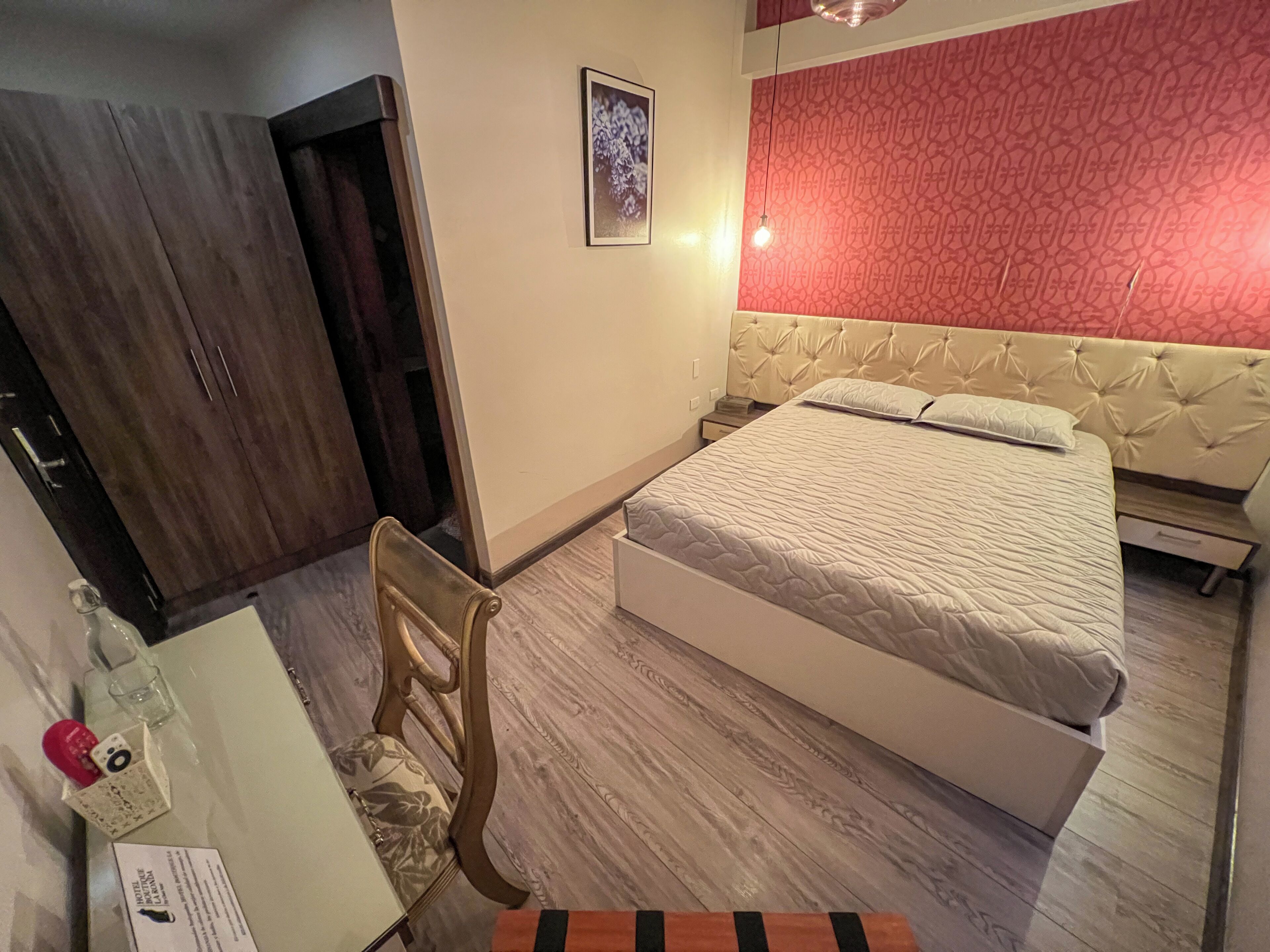 Un dormitorio con cama, una silla, un escritorio y un armario.