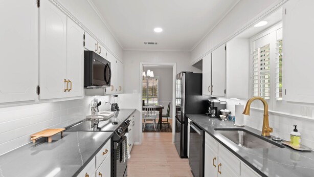 A modern kitchen with white cabinetry, stainless steel countertops, and a central island. - Family Friendly, Updated, Charming Home in North Denton (Denton)