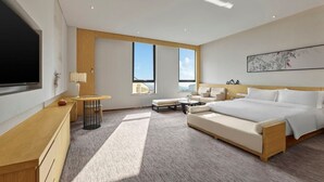 A modern hotel room with a large bed, a desk, a TV, and a window with a city view. - Garrya Xian Lintong (Xi'an)