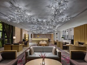 A modern hotel lobby with a central seating area, a reception desk, and a dining area. - Garrya Xian Lintong (Xi'an)