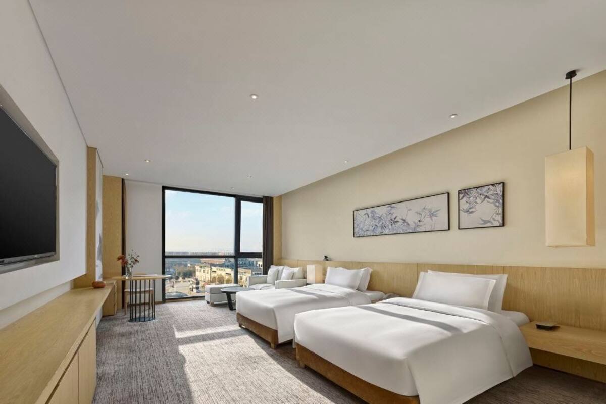 Ein modernes Hotelzimmer mit zwei Betten, einem großen Fenster und Blick auf die Stadt.