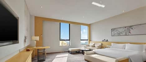 A modern hotel room with a large bed, a desk, a TV, and a window with a city view.